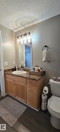 Bathroom featuring a single vanity with a laminate countertop, a rectangular mirror, and an overhead light fixture - 5514 49 Street, Vegreville, AB - Indoor Photo Showing Bathroom
