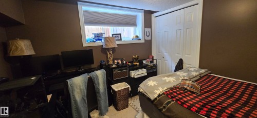 This room features a window providing natural light, warm brown walls, and a white bi-fold closet - 5514 49 Street, Vegreville, AB - Indoor Photo Showing Other Room