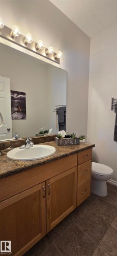Bathroom featuring a vanity with a light wood finish, a stone-patterned countertop, and an integrated sink with a chrome faucet - 5514 49 Street, Vegreville, AB - Indoor Photo Showing Bathroom