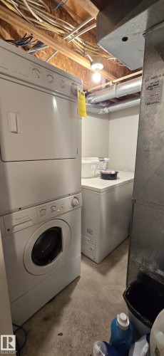 Dedicated laundry area featuring a stackable washer and dryer, concrete flooring, and a chest freezer - 5514 49 Street, Vegreville, AB - Indoor Photo Showing Laundry Room