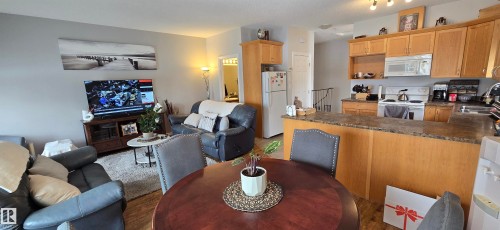Open concept living area with light wood cabinetry, white appliances, and a breakfast bar - 5514 49 Street, Vegreville, AB - Indoor