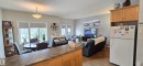 The open concept living area features a dining space with a window overlooking the outdoors, and a living area with light-colored walls and a television - 5514 49 Street, Vegreville, AB  - Indoor 