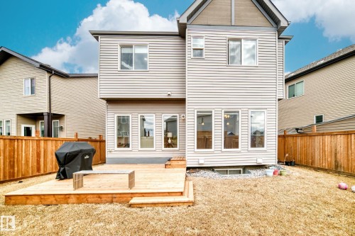 The property features a spacious backyard with a wooden deck, a grassy area, and a privacy fence - 922 173A Street, Edmonton, AB - Outdoor With Exterior