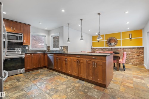The kitchen features stainless steel appliances, wood cabinetry, and a large island with pendant lighting - 101 Westridge Road, Edmonton, AB - Indoor Photo Showing Kitchen