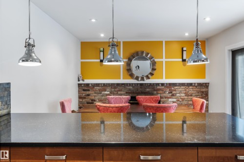 The property features a kitchen island with a dark countertop and wooden cabinetry, illuminated by industrial-style pendant lights - 101 Westridge Road, Edmonton, AB - Indoor