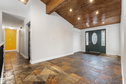 Entryway featuring a decorative dark green front door with frosted glass panels, a wood-paneled ceiling with recessed lighting, and multi-toned stone tile flooring - 101 Westridge Road, Edmonton, AB - Indoor Photo Showing Other Room