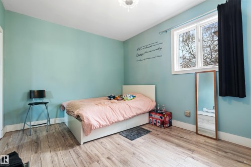 This room features light blue walls, light-colored wood flooring, and a window with white trim - 101 Westridge Road, Edmonton, AB - Indoor Photo Showing Bedroom