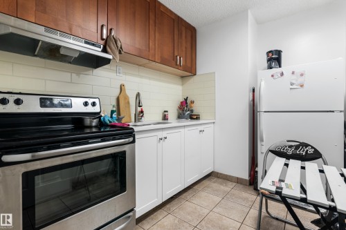 The kitchen features a stainless steel range with an overhead exhaust fan, wood-tone upper cabinetry, and white lower cabinetry - 101 Westridge Road, Edmonton, AB - Indoor Photo Showing Kitchen