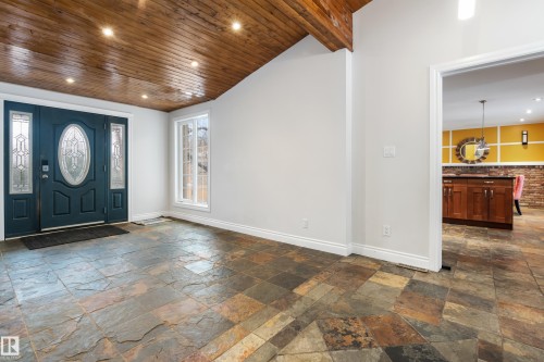 Inviting entryway featuring natural stone tile flooring, a dark blue front door with decorative glass inserts, and a wood plank ceiling with recessed lighting - 101 Westridge Road, Edmonton, AB - Indoor Photo Showing Other Room