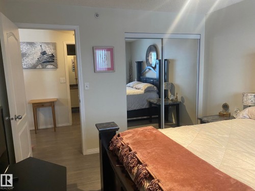 This room features light-colored walls, a mirrored closet, and wood-look flooring - 336 9525 162 Avenue, Edmonton, AB - Indoor Photo Showing Bedroom