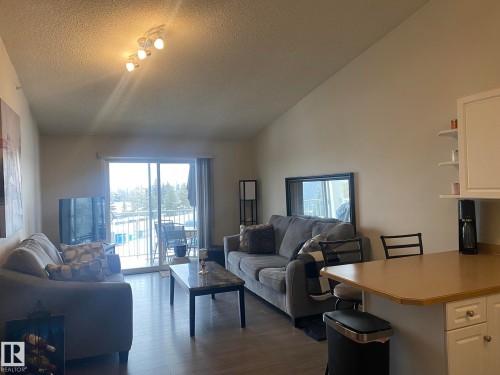 The living area features hardwood style flooring, a sliding glass door leading to a balcony, and track lighting on the ceiling - 336 9525 162 Avenue, Edmonton, AB - Indoor Photo Showing Living Room
