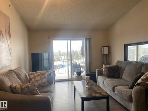 The living room features light-colored walls and a sliding glass door providing access to a balcony with a white railing - 336 9525 162 Avenue, Edmonton, AB - Indoor Photo Showing Living Room