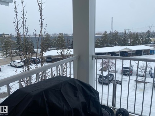 The property features a balcony with white railings, offering views of a snow-covered parking area with covered parking spaces - 336 9525 162 Avenue, Edmonton, AB - Outdoor With Balcony