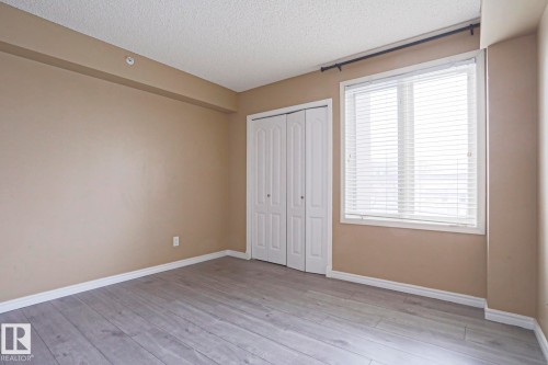 This room features light-colored laminate flooring, neutral-toned walls, and a window with white blinds - 201 10909 103 Avenue Nw, Edmonton, AB - Indoor Photo Showing Other Room