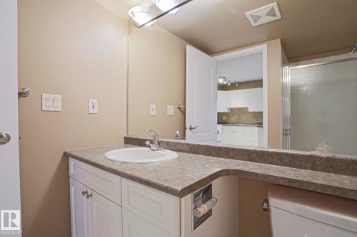 The bathroom features a vanity with a white basin sink and a patterned countertop - 201 10909 103 Avenue Nw, Edmonton, AB - Indoor Photo Showing Bathroom