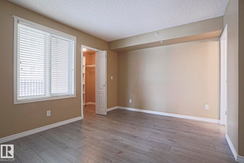 This room features light-colored laminate flooring, neutral wall paint, and a window with horizontal blinds - 201 10909 103 Avenue Nw, Edmonton, AB - Indoor Photo Showing Other Room