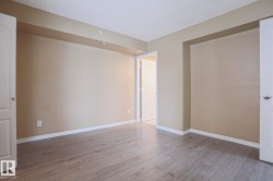 The room features light-colored laminate flooring, neutral-toned walls, white trim, and white doors - 