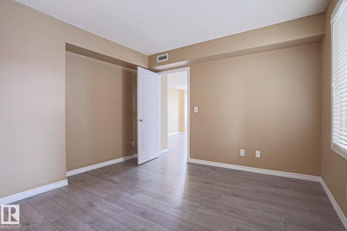 This space features light-colored walls, wood-style flooring, and a window with blinds - 201 10909 103 Avenue Nw, Edmonton, AB - Indoor Photo Showing Other Room