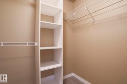 This closet features built-in white shelving units and hanging rods, providing ample storage - 