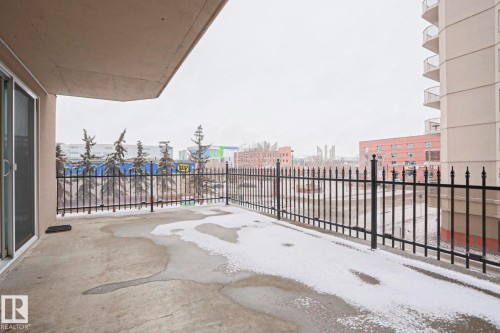 The property features a private balcony with a black wrought iron railing, offering views of the surrounding urban landscape and other residential buildings - 201 10909 103 Avenue Nw, Edmonton, AB - Outdoor With Exterior