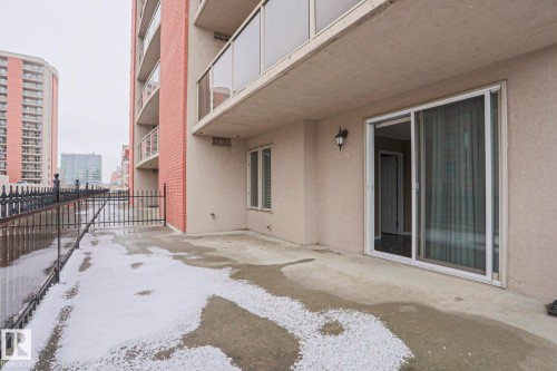 This property features a private outdoor patio with a sliding glass door entry and an exterior wall light fixture - 201 10909 103 Avenue Nw, Edmonton, AB - Outdoor With Balcony With Exterior