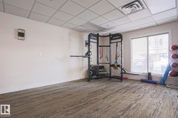 Fitness area featuring patterned carpet flooring, a large window with a roller blind, and recessed lighting in a drop ceiling - 