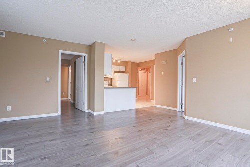 The expansive living area features light-toned flooring, neutral wall paint, and white trim throughout, offering a clean and versatile aesthetic - 201 10909 103 Avenue Nw, Edmonton, AB - Indoor