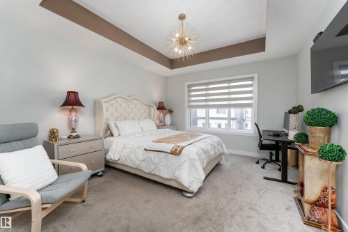 This room features a high ceiling with a tray detail, carpeted flooring, and a large window with horizontal blinds - 993 Berg Pl, Leduc, AB - Indoor Photo Showing Bedroom