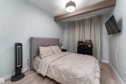 The bedroom features light-colored walls and flooring, with a tufted headboard and light-colored curtains - 