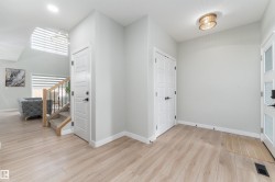 Spacious entry with light-toned flooring, white trim, and a contemporary ceiling light fixture - 