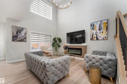 This living space features high ceilings, light wood-style flooring, and an electric fireplace - 