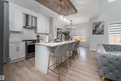 The property features an open concept kitchen and living area, with light wood flooring throughout - 993 Berg Pl, Leduc, AB - Indoor Photo Showing Kitchen With Upgraded Kitchen