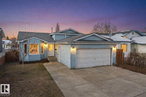 The property features light blue siding, a shingled roof, an attached garage, and a concrete driveway - 2516 42 Street, Edmonton, AB - Outdoor