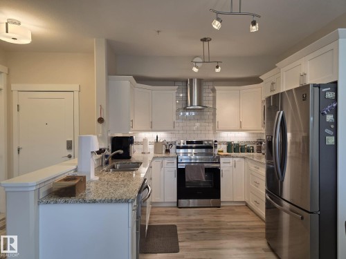 Kitchen featuring white cabinetry, granite countertops, stainless steel appliances, and a subway tile backsplash - 304 5201 Brougham Drive, Drayton Valley, AB - Indoor Photo Showing Kitchen With Double Sink With Upgraded Kitchen