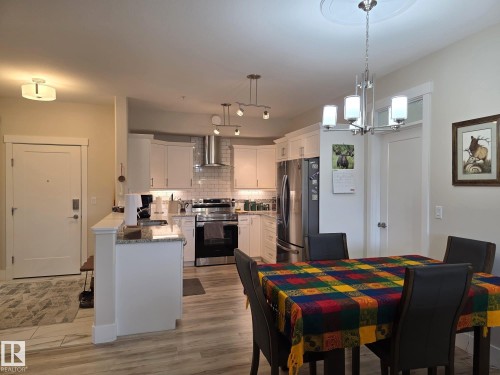 The open concept living area includes a kitchen with white cabinetry, stainless steel appliances, and a tiled backsplash - 304 5201 Brougham Drive, Drayton Valley, AB - Indoor
