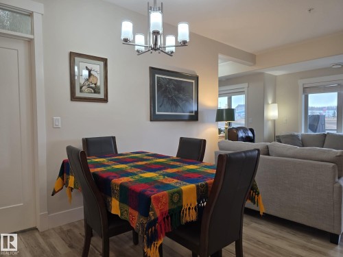 The property features an open-concept living area with light wood-look flooring and a modern chandelier - 304 5201 Brougham Drive, Drayton Valley, AB - Indoor Photo Showing Dining Room