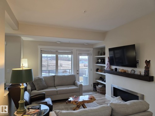 The living area features light-toned walls, a fireplace with a mantel, and built-in shelving - 304 5201 Brougham Drive, Drayton Valley, AB - Indoor Photo Showing Living Room With Fireplace