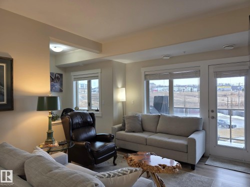 The living area features light-toned walls, a large window, and a glass-paneled door providing outdoor views - 304 5201 Brougham Drive, Drayton Valley, AB - Indoor Photo Showing Living Room