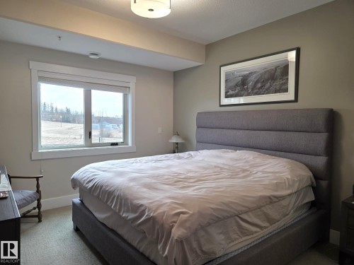 The room features a window with white trim, offering views of the exterior landscape - 304 5201 Brougham Drive, Drayton Valley, AB - Indoor Photo Showing Bedroom