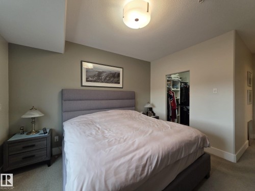 The bedroom features neutral-toned walls, carpeting, and a built-in closet with shelving - 304 5201 Brougham Drive, Drayton Valley, AB - Indoor Photo Showing Bedroom
