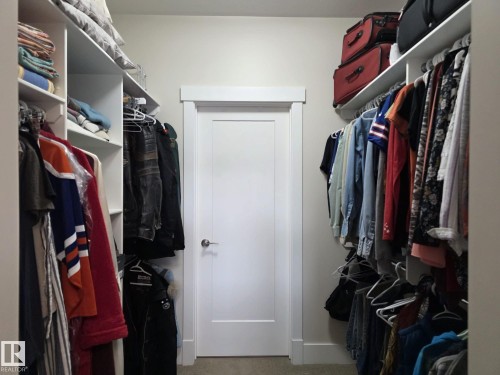 Walk-in closet with built-in shelving, hanging rods, and a white door with a silver handle - 304 5201 Brougham Drive, Drayton Valley, AB - Indoor With Storage