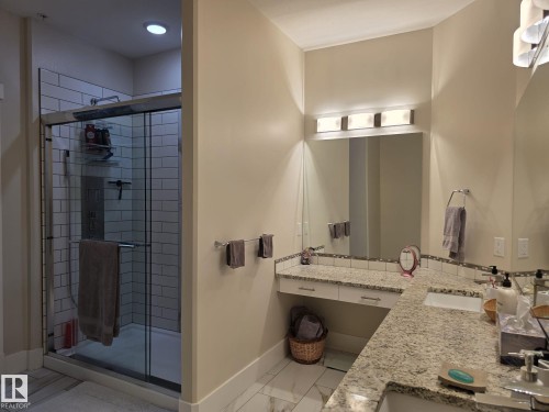 The bathroom features a spacious walk-in shower with subway tile, a dual vanity with granite countertops, and built-in lighting fixtures above the mirror - 304 5201 Brougham Drive, Drayton Valley, AB - Indoor Photo Showing Bathroom