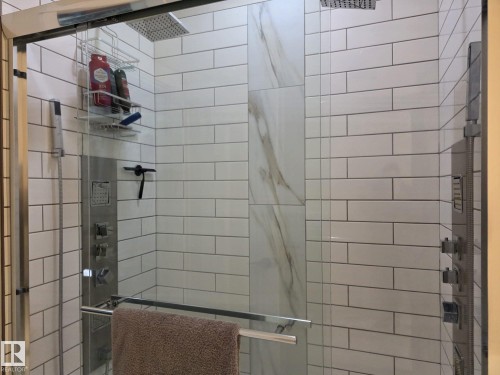 The shower features white subway tile, a rainfall showerhead, and a multi-function shower panel with several controls - 304 5201 Brougham Drive, Drayton Valley, AB - Indoor Photo Showing Bathroom