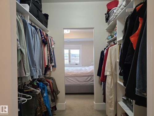 This walk-in closet features carpeted flooring and built-in shelving and hanging rails for storage - 304 5201 Brougham Drive, Drayton Valley, AB - Indoor With Storage