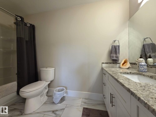 Bathroom featuring a vanity with a light-colored granite countertop, a shower-tub combination, and tiled flooring - 304 5201 Brougham Drive, Drayton Valley, AB - Indoor Photo Showing Bathroom