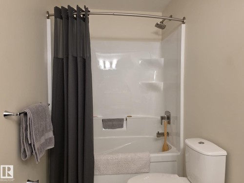 Bathroom featuring a shower/tub combination with a curved shower rod and a modern toilet - 304 5201 Brougham Drive, Drayton Valley, AB - Indoor Photo Showing Bathroom