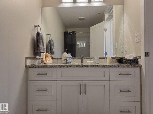 Bathroom vanity featuring a light-colored granite countertop, a single basin sink, and shaker-style cabinetry with chrome hardware - 304 5201 Brougham Drive, Drayton Valley, AB - Indoor Photo Showing Bathroom