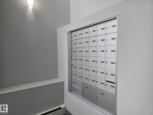 Wall-mounted mailboxes with a modern sconce providing ambient lighting - 304 5201 Brougham Drive, Drayton Valley, AB - Indoor Photo Showing Other Room