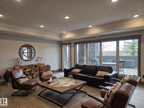 Spacious living area featuring recessed lighting, a decorative mirror, and large windows with outdoor patio access - 304 5201 Brougham Drive, Drayton Valley, AB - Indoor Photo Showing Living Room