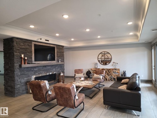 The living area features a stone-clad fireplace with a hearth, recessed lighting, and crown molding - 304 5201 Brougham Drive, Drayton Valley, AB - Indoor Photo Showing Living Room With Fireplace